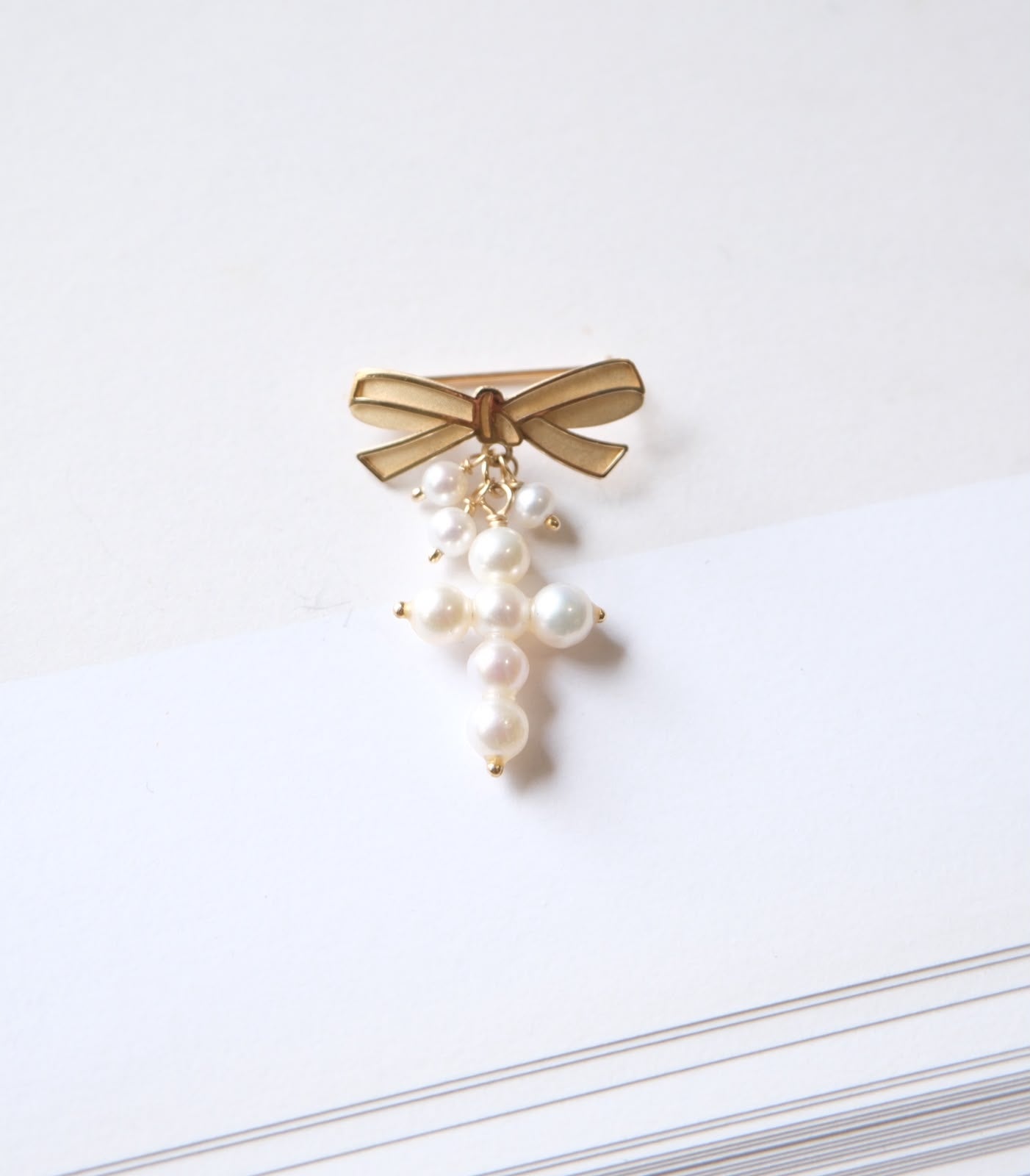 Cruz de perlas con broche de moño en oro 14k